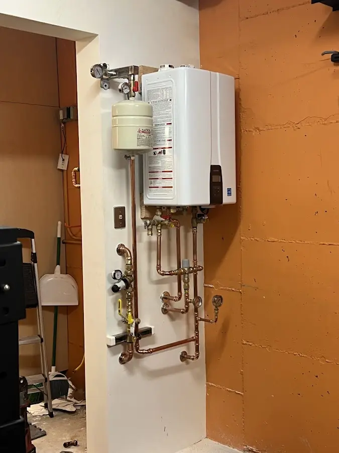 Plumbing technician inspecting water heater connections in Mundy